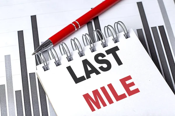 LAST MILE text written on gray background with pen and calculator