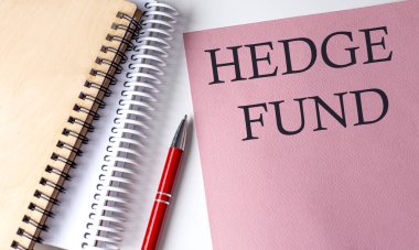 Pembe kağıda beyaz arka planda ofis araçları olan HEDGE FUND sözcüğü