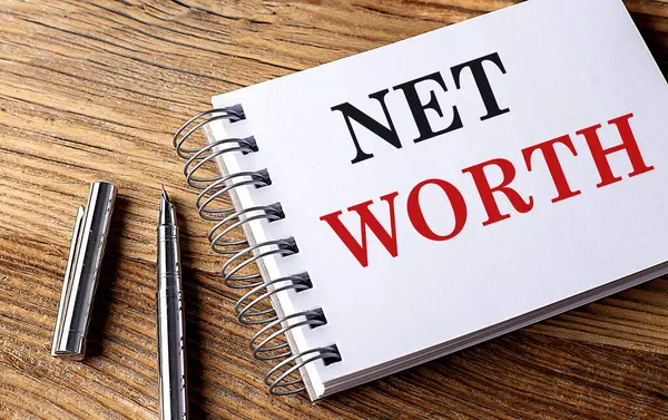 NET WORTH text on a notebook with pen on wooden background