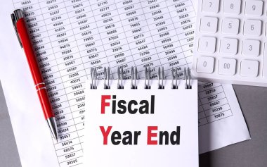 FISCAL Yıl Sonu Gri bir arkaplan üzerinde kalem, hesap makinesi ve grafik ile defter üzerinde metin