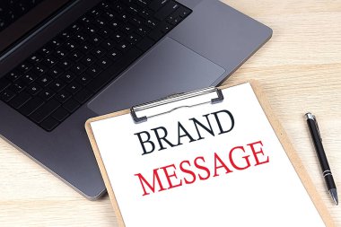 Diz üstü bilgisayarda kağıt panoya yazılmış Brand MESSAGE metni