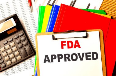 FDA APPROVED metin bir kağıt pano üzerinde çizelge ve hesap makinesi ile yazılmış