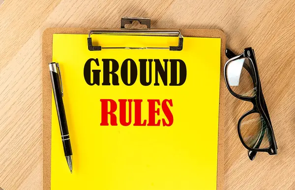 GROUND RULES text on yellow paper on wooden background