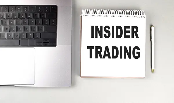 stock image INSIDER TRADING text on a notebook with laptop and pen