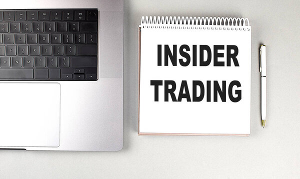 INSIDER TRADING text on a notebook with laptop and pen