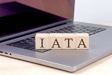 Diz üstü bilgisayarda ahşap bir blokta IATA kelimesi, iş kavramı
