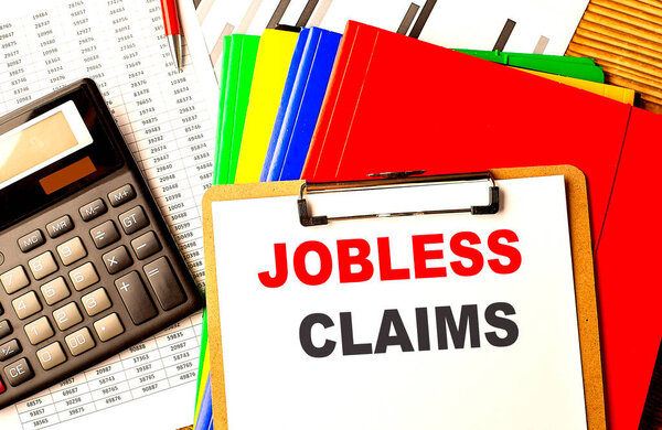 JOBLESS CLAIMS text written on a paper clipboard with chart and calculator