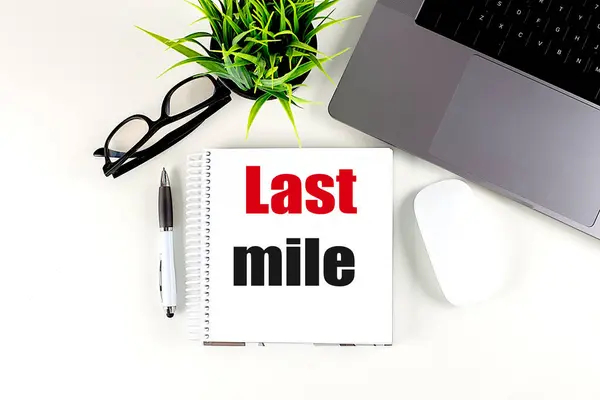 LAST MILE text on a notebook with laptop, mouse and pen .