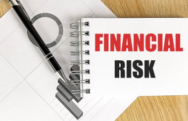 Ahşap zemin üzerinde çizelgesi olan bir defter üzerindeki FINANSAL RISK metni. 