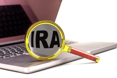 IRA word on a magnifier on laptop , white background .  clipart