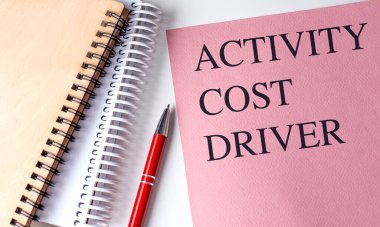 ACTIVITY COST DRIVER text on a pink paper with notebooks .  clipart