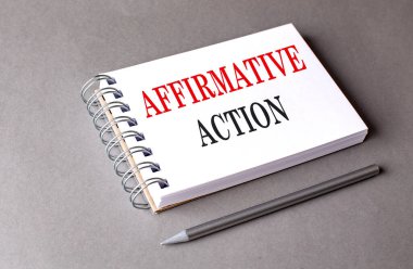 Gri arkaplan üzerine bir defter üzerinde AFFIRMATIVE Action metni 