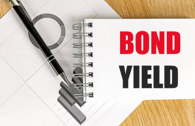 Tahta zemin üzerinde çizelgesi olan bir defter üzerindeki BOND YIELD metni. 