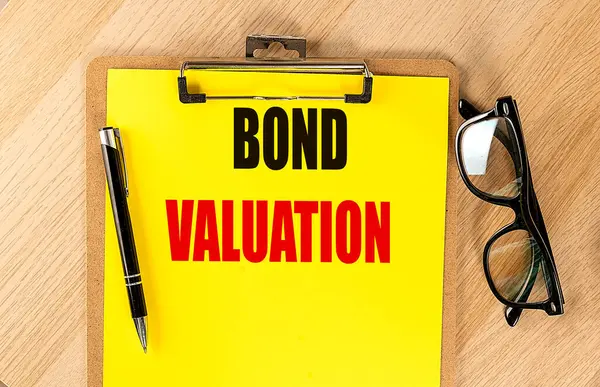 stock image BOND VALUATION text on a yellow paper on clipboard with pen and glasses. 