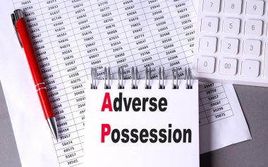 ADVERSE POSSESSION text on a notebook with chart , pen and calculator.  clipart