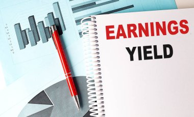 EARNINGS YIELD text on a notebook on chart background  clipart