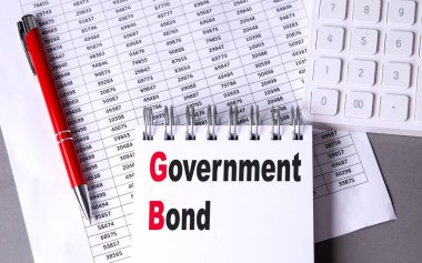 GOVERNMENT BOND text on a notebook with chart , pen and calculator. 