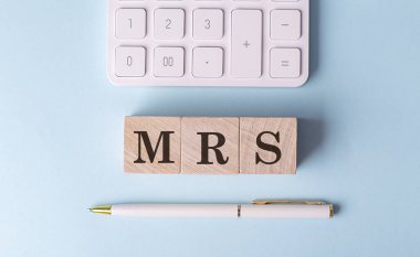 MRS word on a wooden block with pen and calculator on blue background  clipart