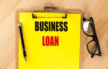 Panodaki sarı kağıtta kalem ve gözlüklü bir iş kredisi metni. 