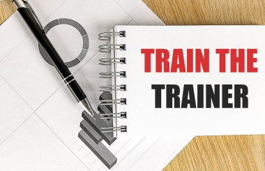 Not defterine ahşap bir arkaplan çizelgesiyle TREN The Trainer metni yaz.