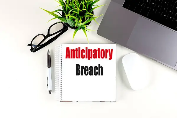 Stock image ANTICIPATORY BREACH text on a notebook with laptop, mouse and pen . 