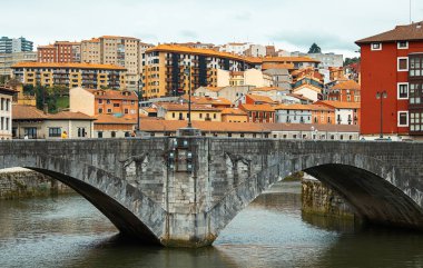 Avrupa 'nın arka planında renkli binalar olan nehir üzerindeki taş köprü