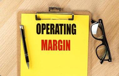 Kağıt üzerinde kalem ve gözlüklü sarı bir kağıt üzerinde MARGIN metni OPERING. 