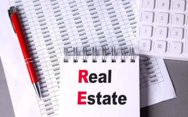 Çizelge, kalem ve hesap makinesi olan bir dizüstü bilgisayarda emlak metni. 