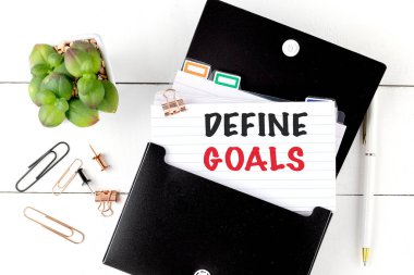 DEFINE GOALS text on a note with office supplies .  clipart