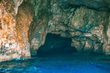  Kayalık duvarları ve derin mavi suları olan tenha bir deniz mağarası gizemli ve huzurlu bir kıyı manzarası sunuyor.. 