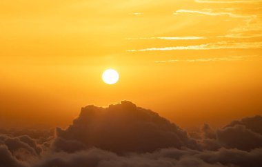  Pofuduk bulutların üzerinde parlayan güneşli altın gün batımı ılık ve huzurlu bir atmosfer yaratıyor. . 