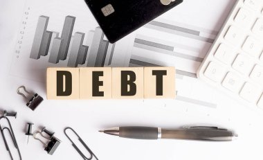 Tahta bloklarda mali tabloları, kredi kartı, hesap makinesi ve ofis malzemeleriyle borç metni. . 