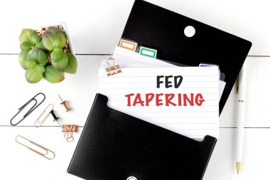 Ofis malzemeleri ve küçük bir saksı bitkisi ile çevrili siyah organizatörlü bir indeks kartı üzerinde besin inceltici metin. 