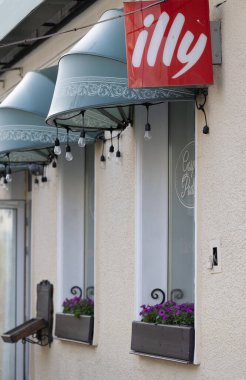 Bialystok, Poland- 19 Mayıs 2025 'te mavi tenteli, asılı ampullü ve çiçekli bej renkli bir duvardaki kafeterya tabelası