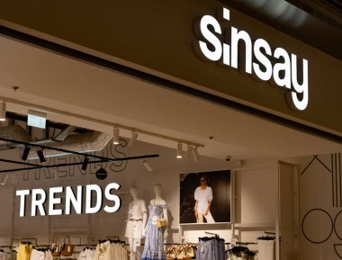 Bialystok, Poland- 27 Mayıs 2025: Sinsay moda mağazası girişi aydınlatılmış logo, yaz kıyafetleri ve moda tabelasında mankenler. 