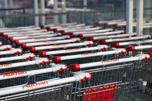 Bialystok, Poland- 27 Mayıs 2025: Auchan marka alışveriş arabaları güneş ışığı altında mağazanın önünde sıraya dizildi. 