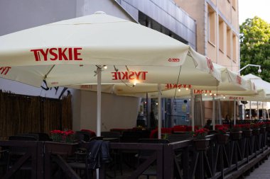 Bialystok, Poland- 27 Mayıs 2025 Tyskie marka şemsiyeler ve korkuluklar boyunca saksıda duran çiçeklerle birlikte açık hava restoranı. 