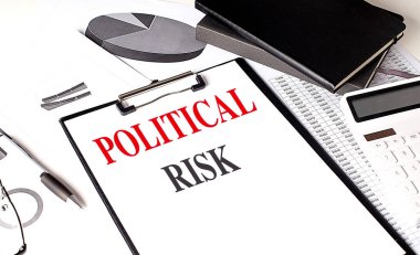 Çizelgeler, hesap makinesi, defter ve kalemle dolu bir masanın üzerinde siyasi risk içeren bir pano . 