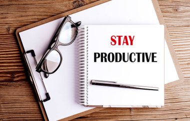 Kalem, not tahtası ve ahşap masasında gözlük olan sarmal bir defterde üretken bir ifade olsun. . 