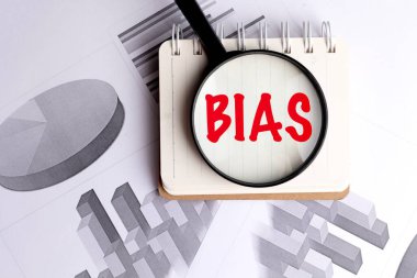 Önyargı kelimesi kırmızı harflerle büyütüldü. Not defterindeki camla. İş çizelgesiyle birlikte. .