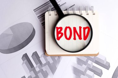 Büyüteç, arka planda mali tablolarla birlikte kırmızı harflerle yazılmış tahvil kelimesine odaklanıyor. . 