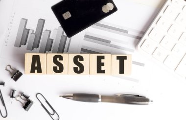 Tablolar, kredi kartı, sikkeler, dolma kalem, hesap makinesi ve ofis malzemeleriyle dolu bir masanın üzerindeki tahta bloklar.. 