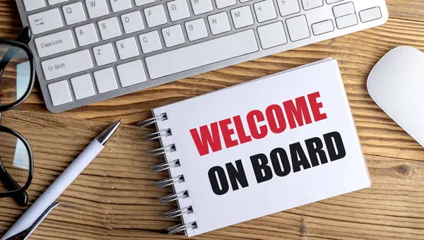 Tahta masanın üzerinde kalem, klavye ve fare olan spiral defter üzerindeki tahta metne hoş geldiniz. . 