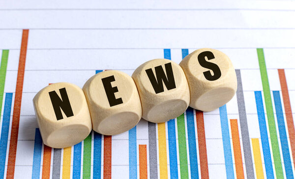 News word on wooden round blocks placed over colorful bar graph on a white background .