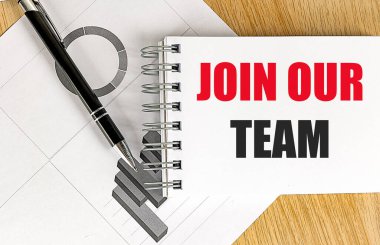 Sözcüklerin yazılı olduğu defter, masamızdaki takımımıza tahta bir arka planda kalem ve iş çizelgeleriyle katılıyor.. 