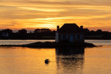 Gün batımında nehir kenarındaki ev