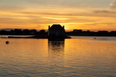 Gün batımında nehir kenarındaki ev