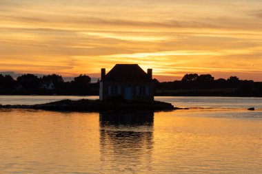 Gün batımında nehir kenarındaki ev