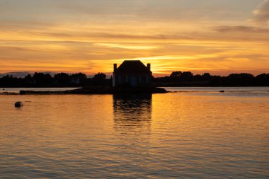 Gün batımında nehir kenarındaki ev