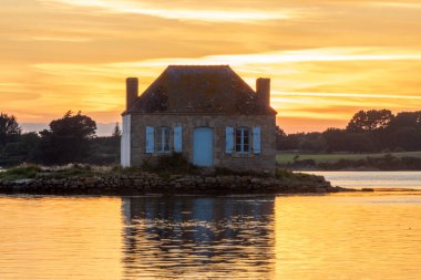Gün batımında nehir kenarındaki ev